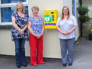 Linda Durno, Avril Balmforth and Tracy Cornelius, Head teacher, with the first defibrillator now in place at Kington St Michael School